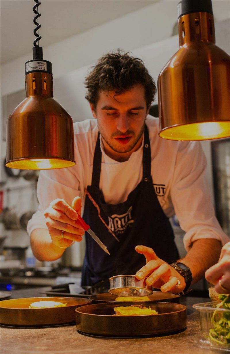 Site do Sabor & Cia — chef finalizando pratos sob luminárias de cobre